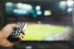 Main qui tient une télécommande pour la télévision en arrière plan