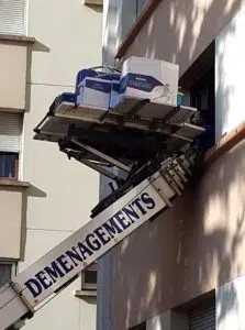 Photo d'un plateau de monte-meubles appuyé sur une fenetre et de cartons GD