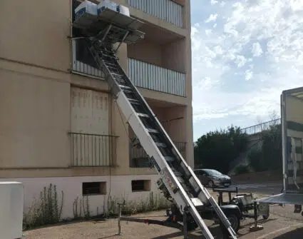 Photo d'un monte-meubles tracté installé sur la facade d'un immeuble